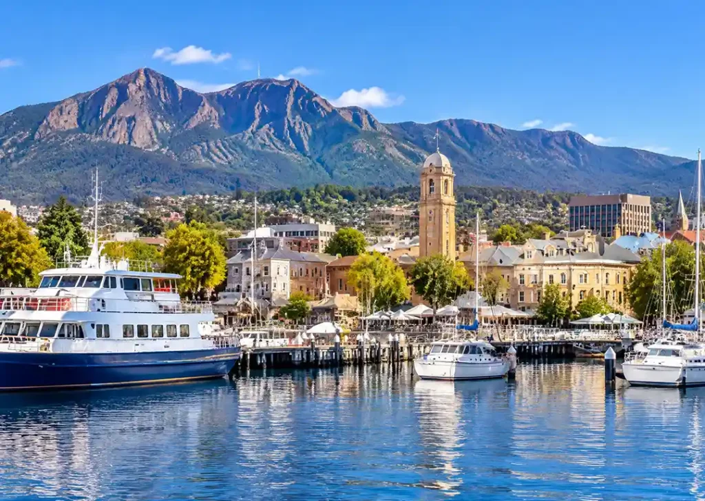 Scenic view of Hobart harbour and docks with moored boats and Mount Wellington rising in the background under a blue sky